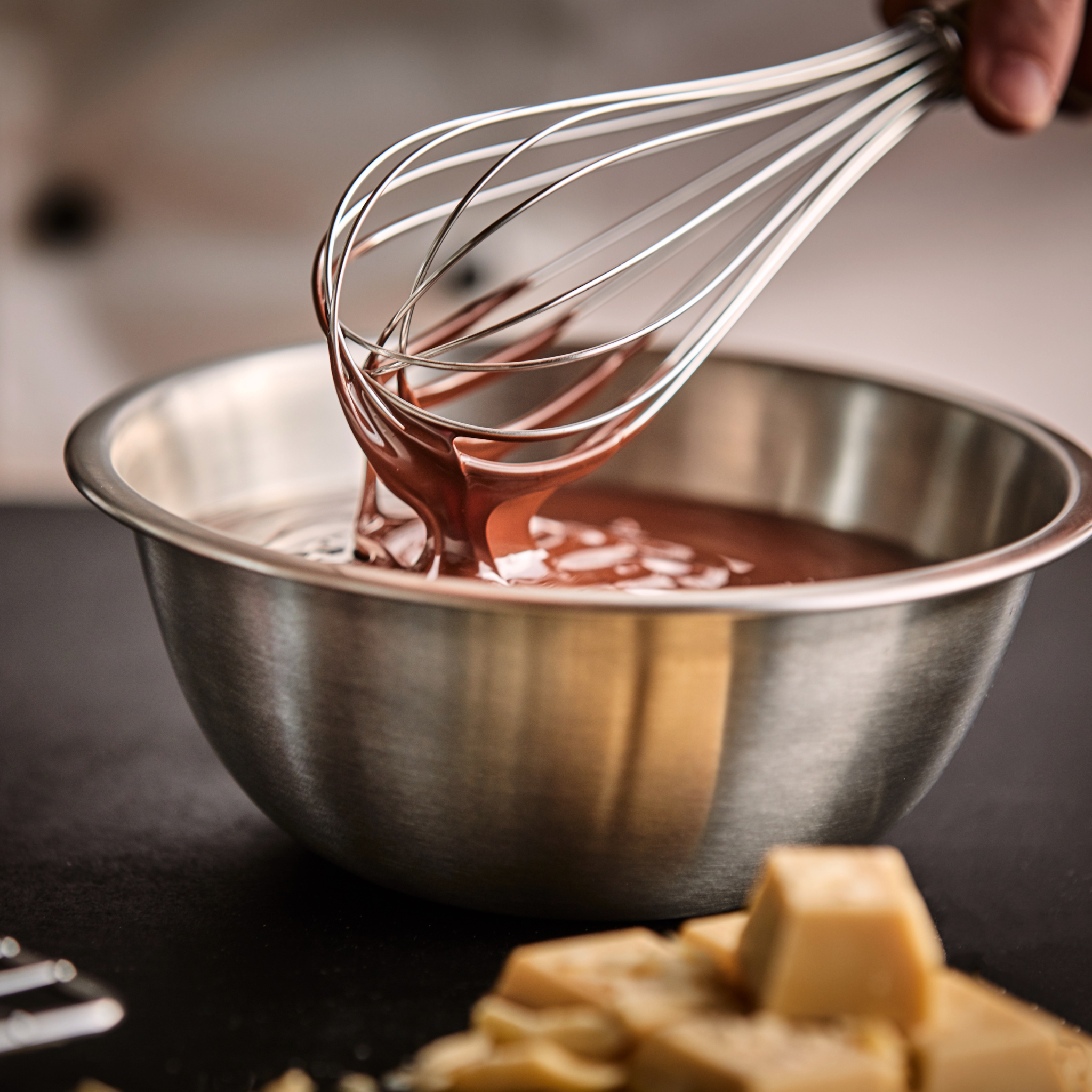Schüssel mit geschmolzener Callebaut Kuvertüre und Schneebesen – belgische Schokolade für Profis. Ideal für Gastronomiebedarf, Bäckereibedarf und Konditoreibedarf. Jetzt Callebaut Kuvertüre kaufen online in Großpackung.